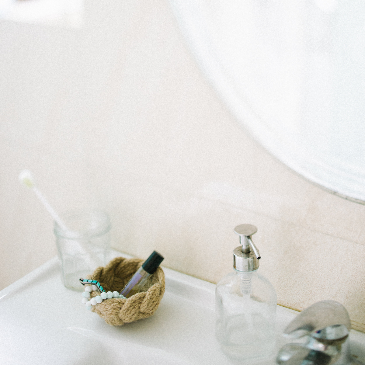Minimalist bathroom sink with a toothbrush in a glass, woven basket, and soap dispenser