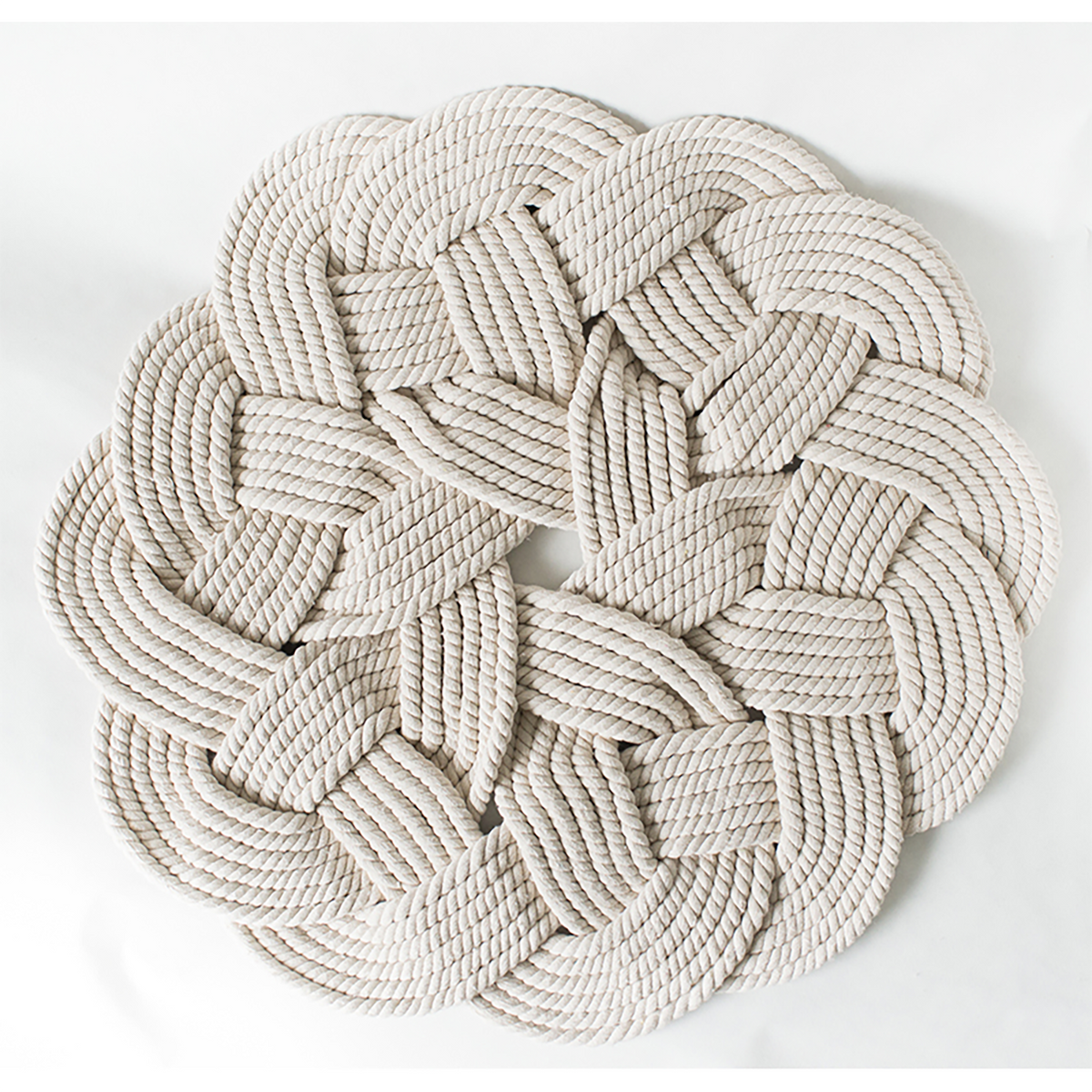 Large round braided cotton rug with woven knot design on a white background